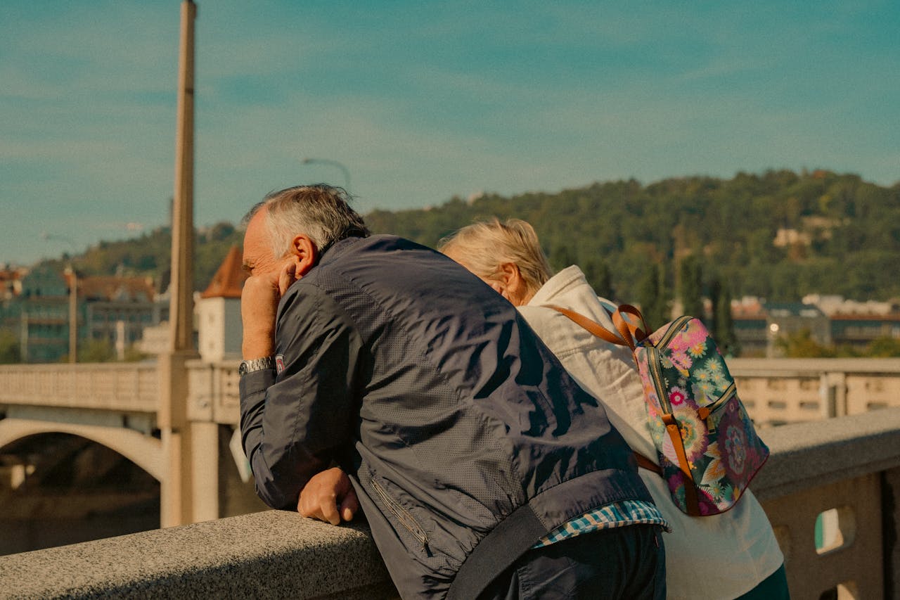An elderly couple enjoys a sunny day overlooking Pragues charming architecture.