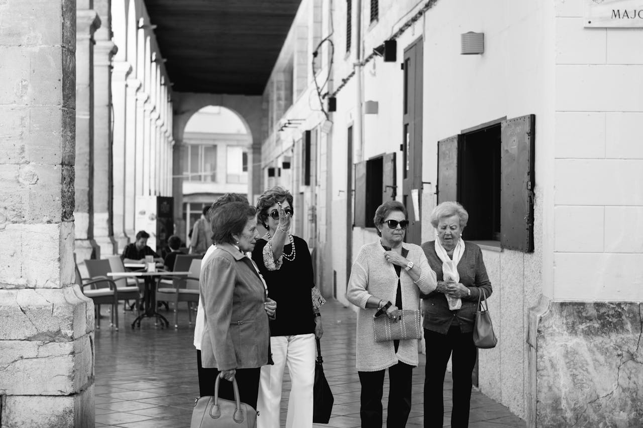 Four senior women enjoying a leisurely day in a cityscape setting, embracing urban life.